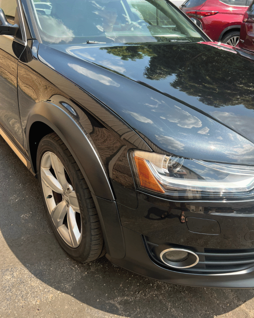 A black Audi, once badly damaged in the front bumper and fender, is now beautifully restored. The car now shows no signs of damage, and looks much brighter.
