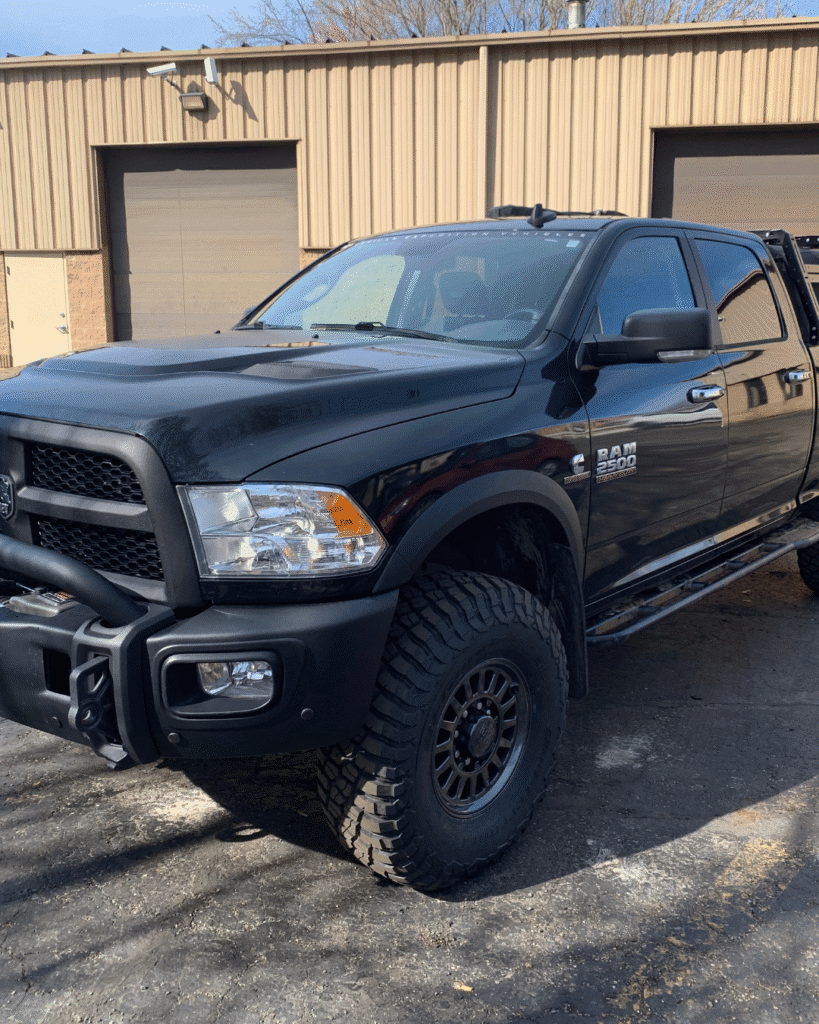 A black Ram 2500 after repair from Evolve Auto. The car's front side and tire have both been restored. The car shines beautifully, with a new gloss.