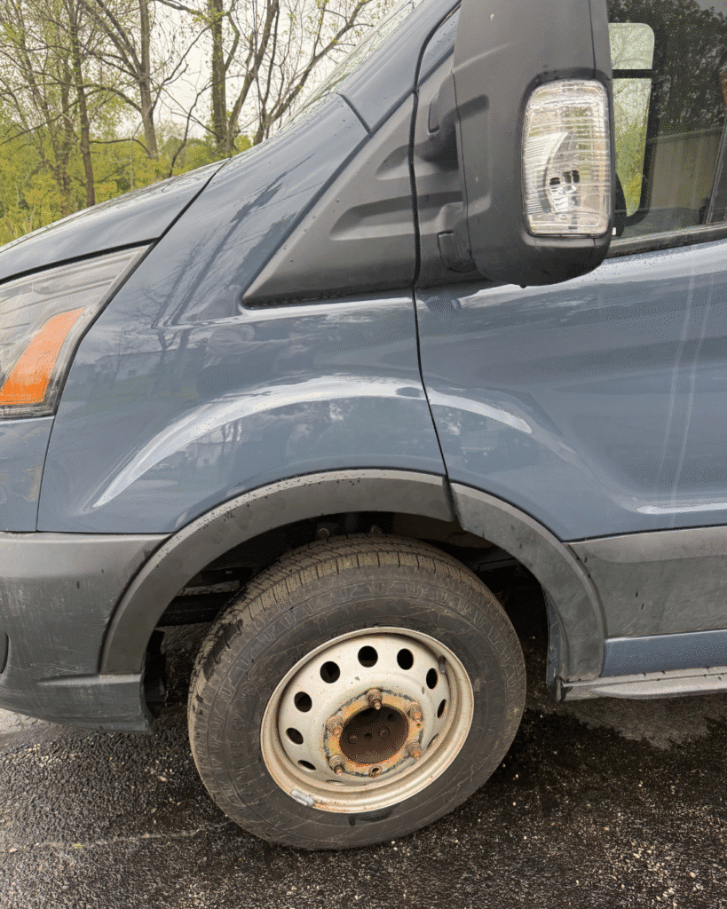 A blue 2024 Ford Transit 2500, after repairs, no longer has damage on its left front end. The car is now glossier and more refined.
