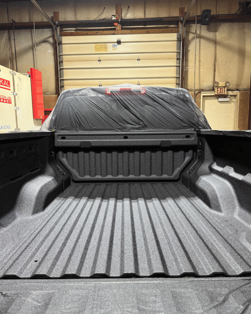 The back of a pickup truck after our sprayed bed liner services. The truck's liner is heavy-duty, clean, well painted, and brand new.