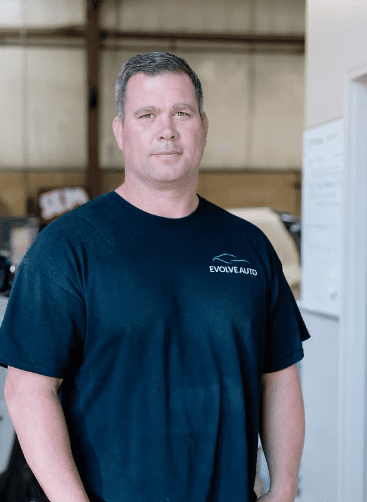 Bill Foster, one of the co-owners of Evolve Auto. Bill has grey hair, brown eyes, and wears a black Evolve Auto tshirt.