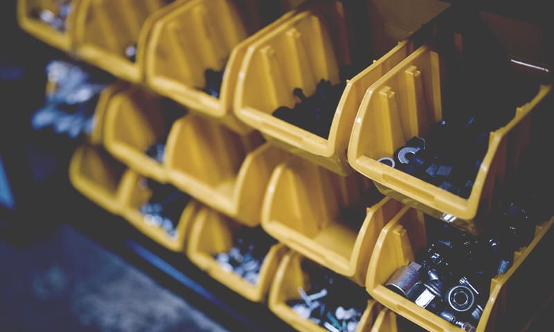 Yellow shelf bins that hold a variety of different nuts, bolts, and parts for car repairs