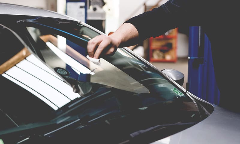 A man wiping off the windshield of a car
